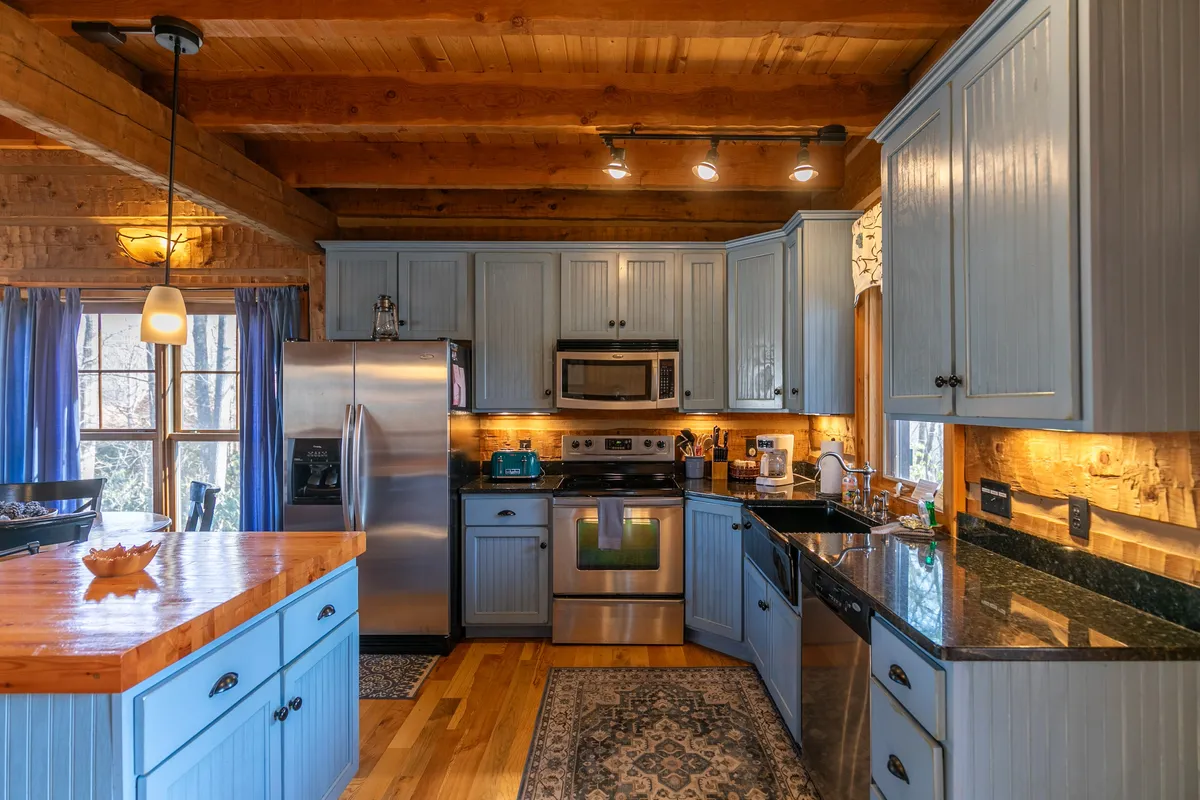 A modern, fully equipped kitchen featuring a central island with granite countertops, gleaming stainless steel appliances, and blue cabinetry. The layout is open and inviting, ideal for preparing meals and socializing with family and friends.